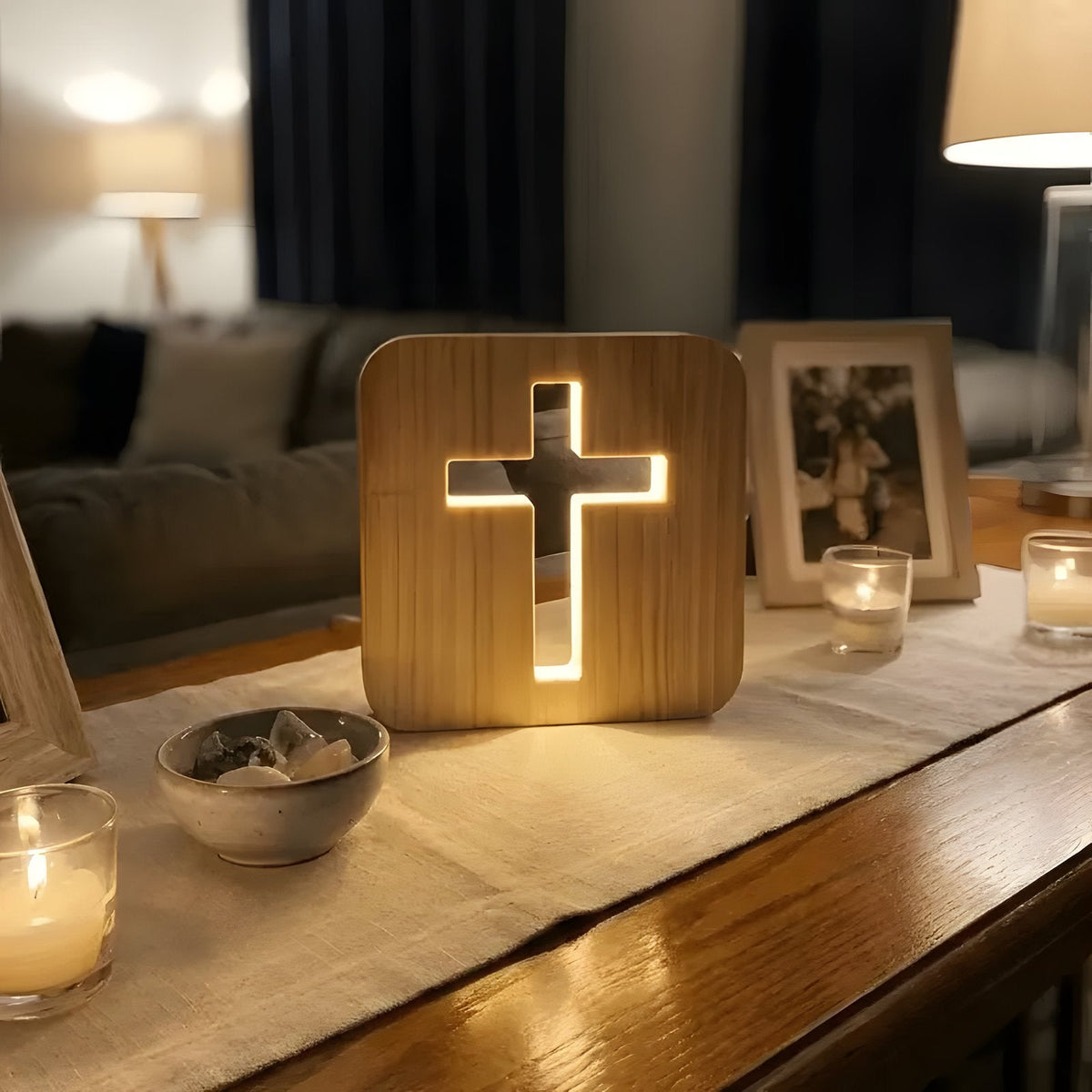 Wooden cross lamp on cozy tabletop with candles and photo frame