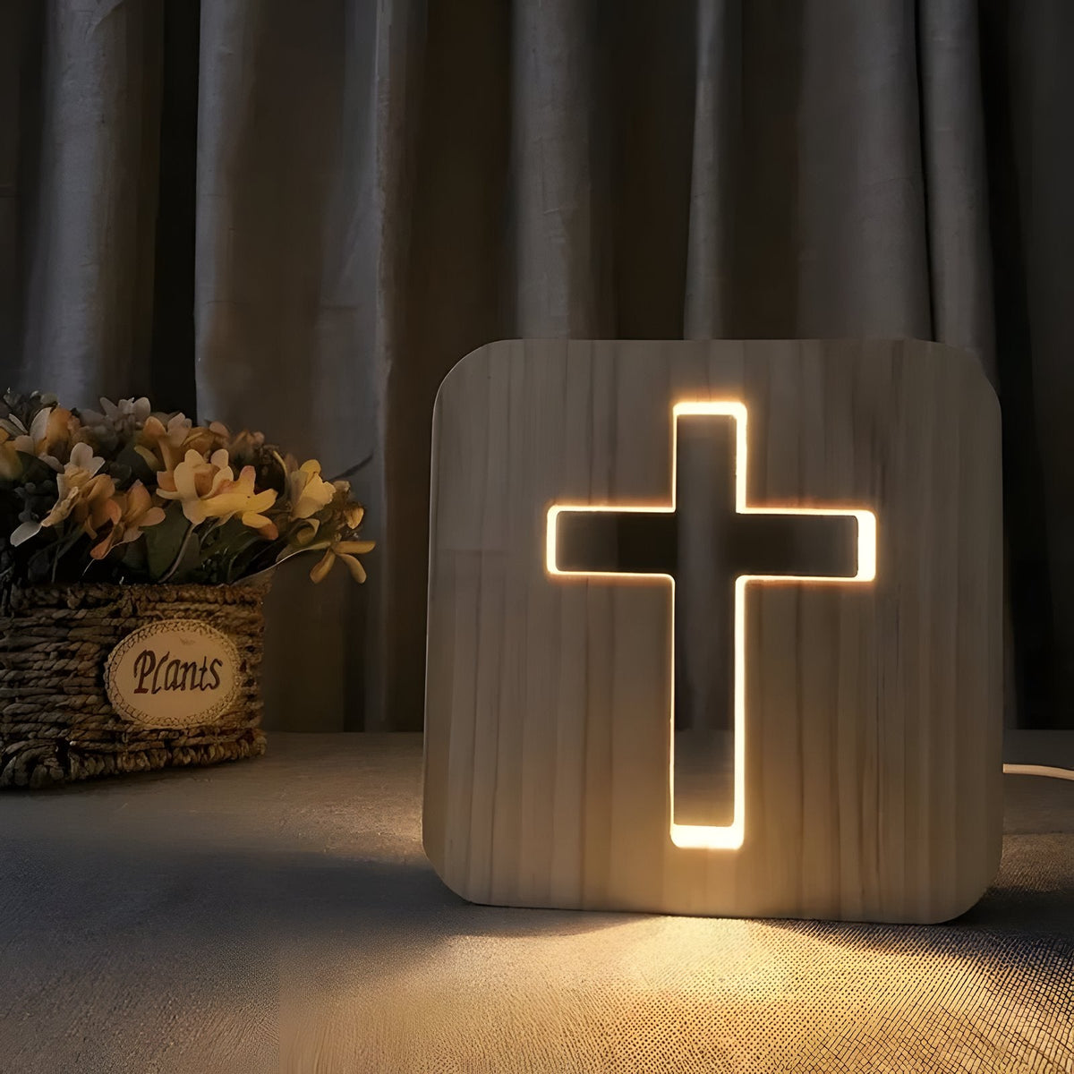 Wooden cross lamp glowing beside a basket of dried flowers