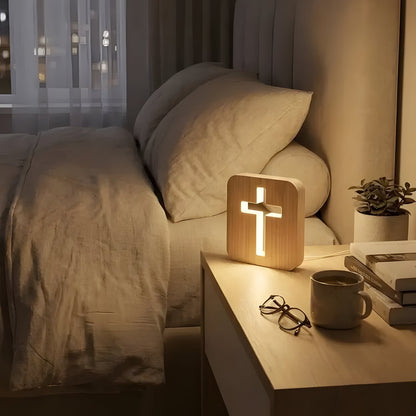 Wooden cross lamp on bedside table next to a soft pillow